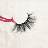 Mink eyelashes held with pink applicator against a neutral background.