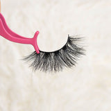 Mink eyelashes held by a pink applicator.